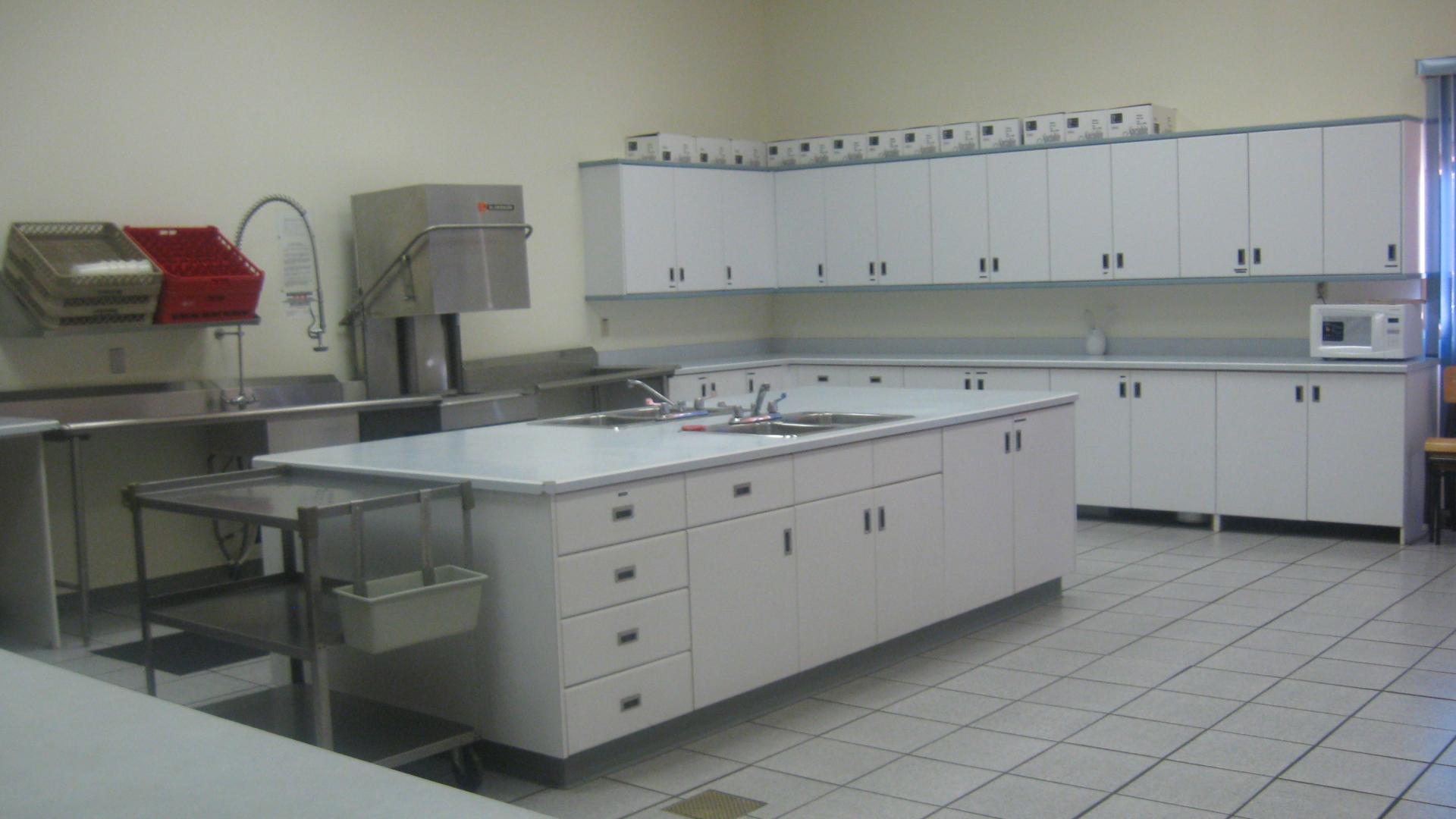 Spacious kitchen / food prep area. There are many cabinets and lots of table surface. There are also some kitchen appliances at the back of the room.