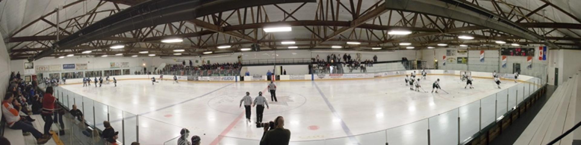 Interior panorama view of hockey rink with hockey game in progress.