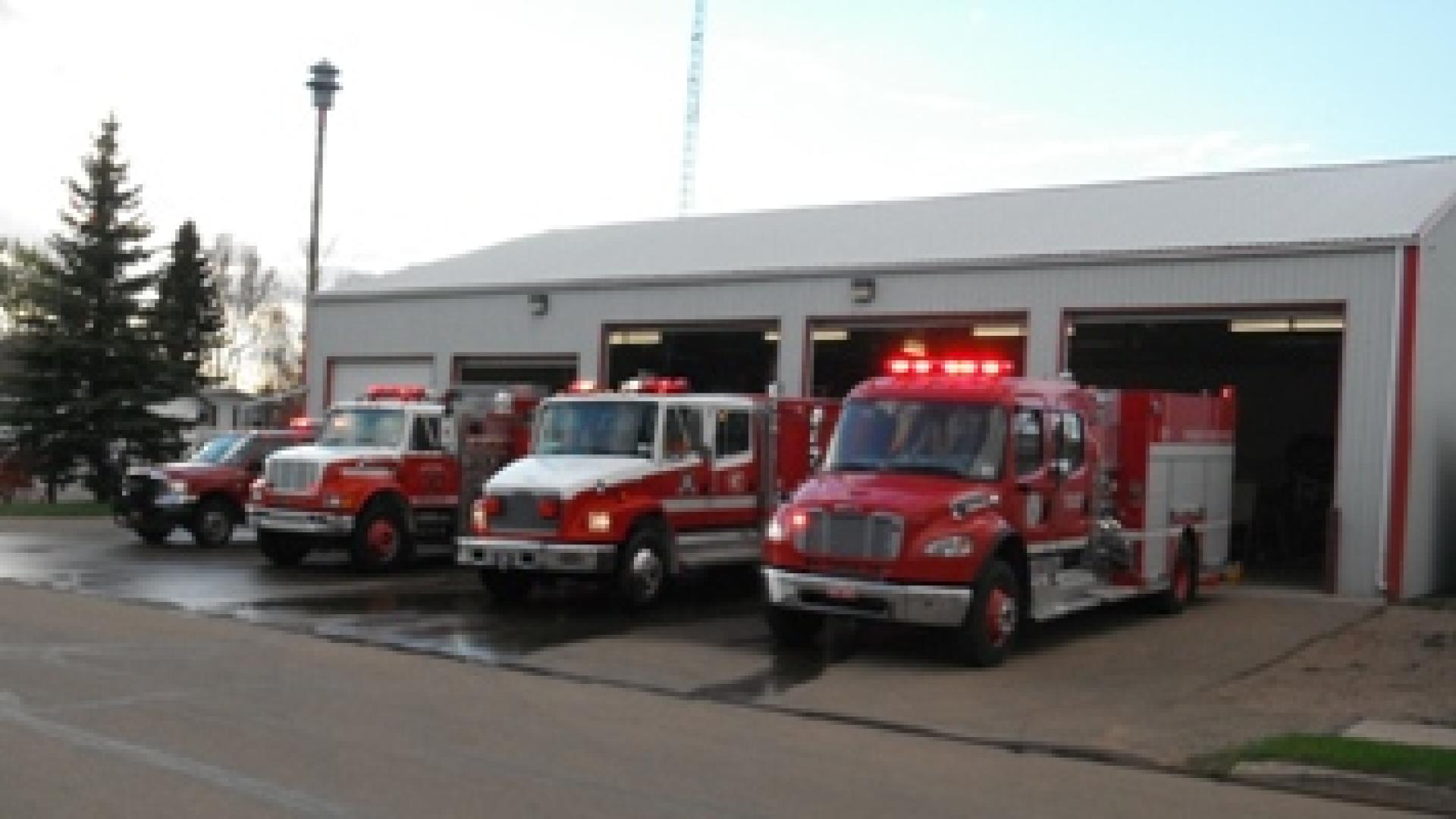 Killam Fire Department fire fleet outside of fire station. There are 3 red and white fire trucks in the fleet