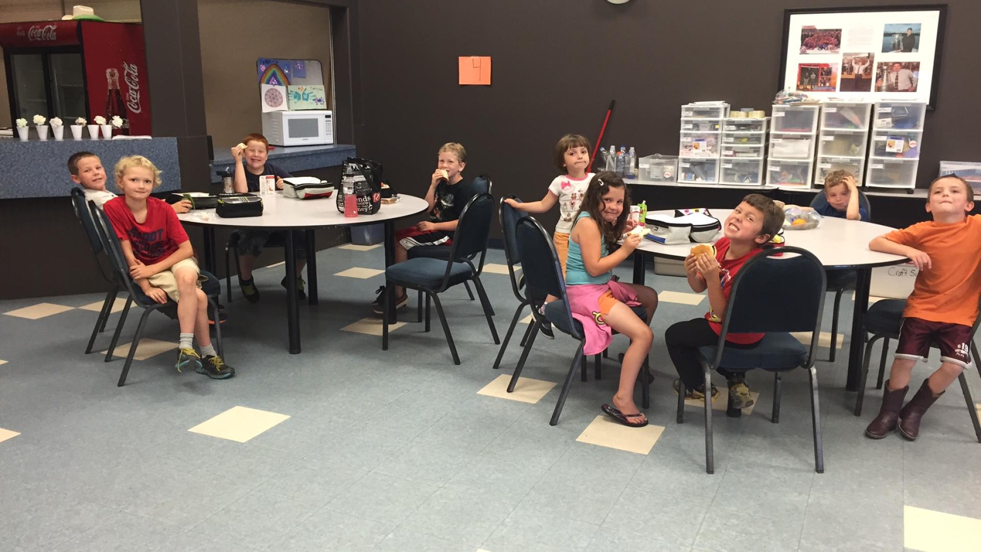Multi-purpose room in use. There are women seated throughout the room around tables.