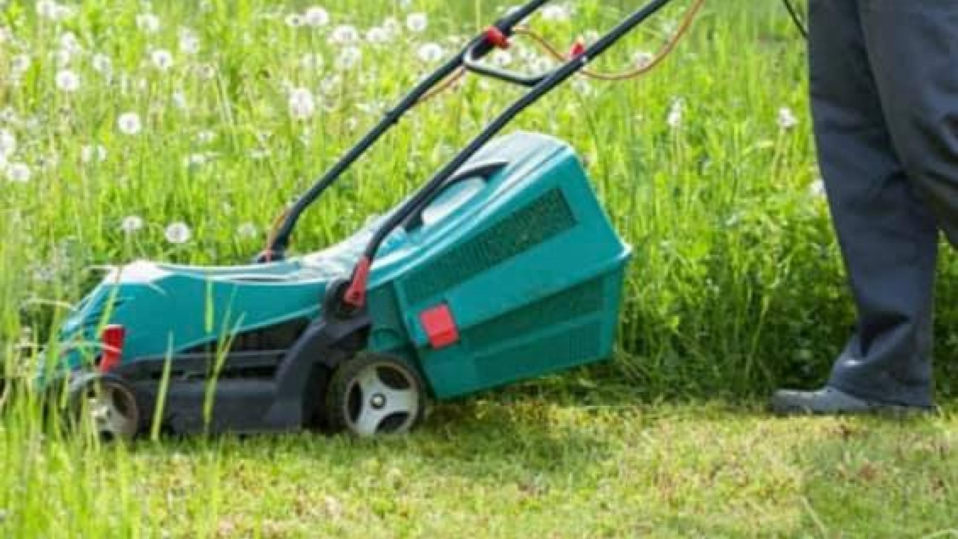 lawn mower cutting grass and a person pushing it