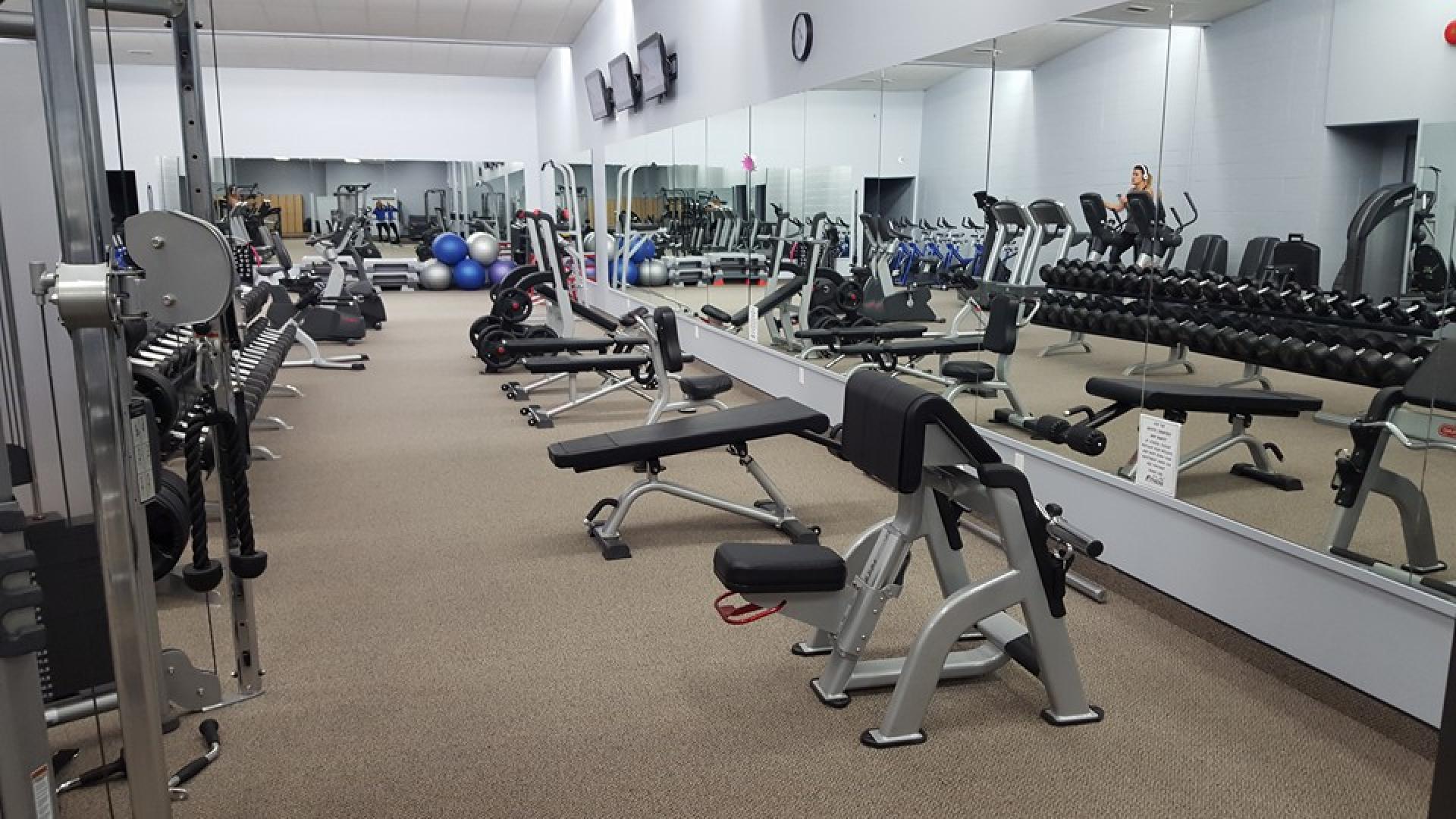 Interior of fitness centre. There are some weight benches throughout the room.