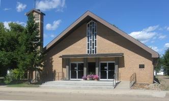 Exterior of St. Joseph Catholic Church. It is a brown building with a triangular roof.