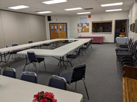 Large room with tables in the middle of and surrounding the room. 