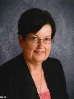 Headshot of Brenda McDermott. There is a woman with glasses, black hair and a black blouse in front of a gray background.