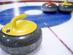 Curling rocks on curling play area. The curling rocks are on a blues circle. The rocks are yellow and red respectively.