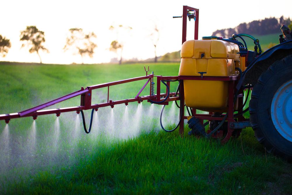 tractor spraying liquid onto a green field 